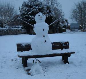 Snow dog and above snow man resting on a bench