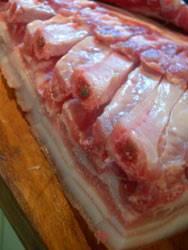 Photo of an uncooked belly of pork joint skin side down